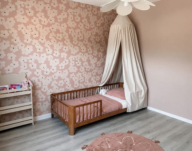 Oudroze bloemenbehang met hemeltje boven het peuterbed
